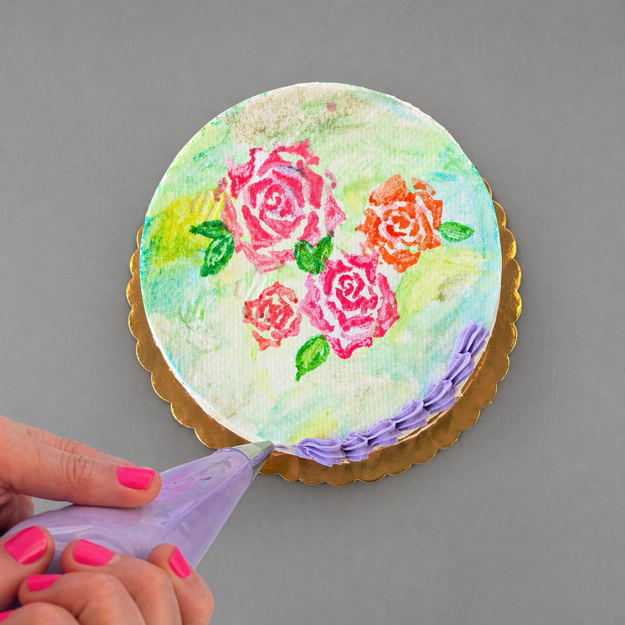 A customer pipes on purple frosting to a watercolor-painted cake for Mother's Day at Cake Hoopla.