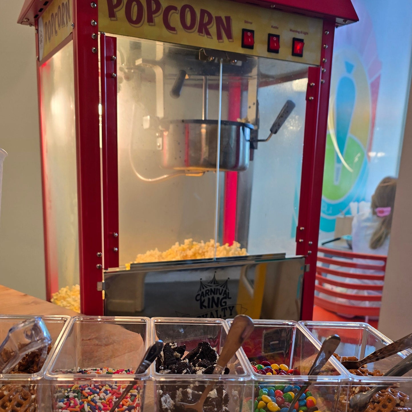 Hot popcorn in machine with various toppings ready for popcorn party.