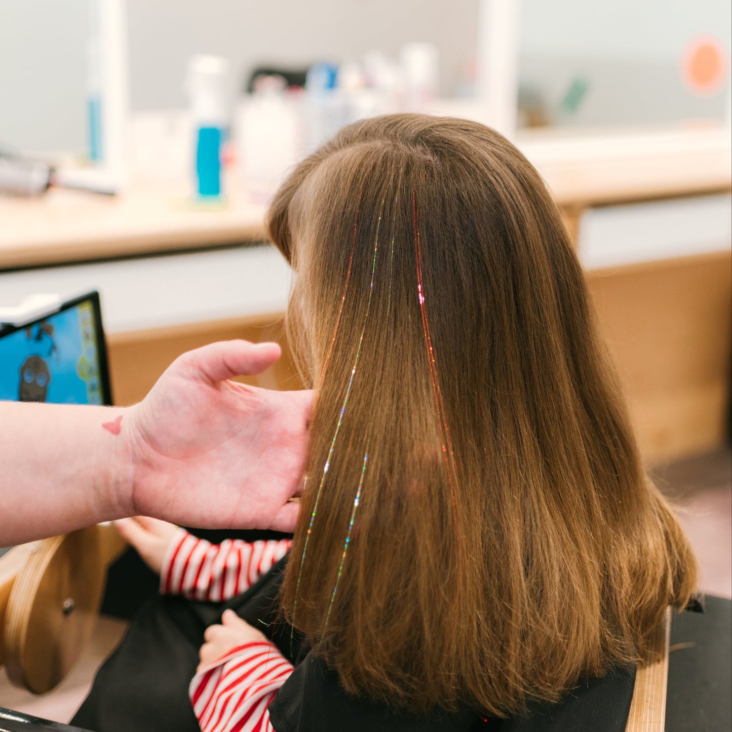 A girl with long hair shows off several sparkle strands by Sit Still Salon in Portland.