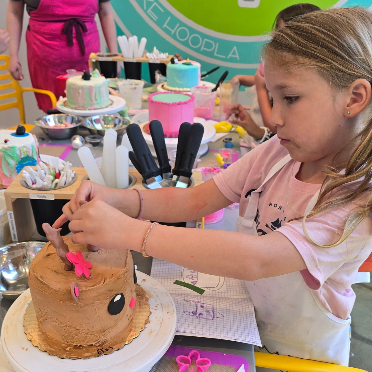 A girl focuses as she adds details, like antlers, to her reindeer cake.