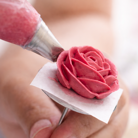 Pink frosting rose being created with a piping bag for a DIY cake-decorating class at Cake Hoopla in Tigard, near Portland.