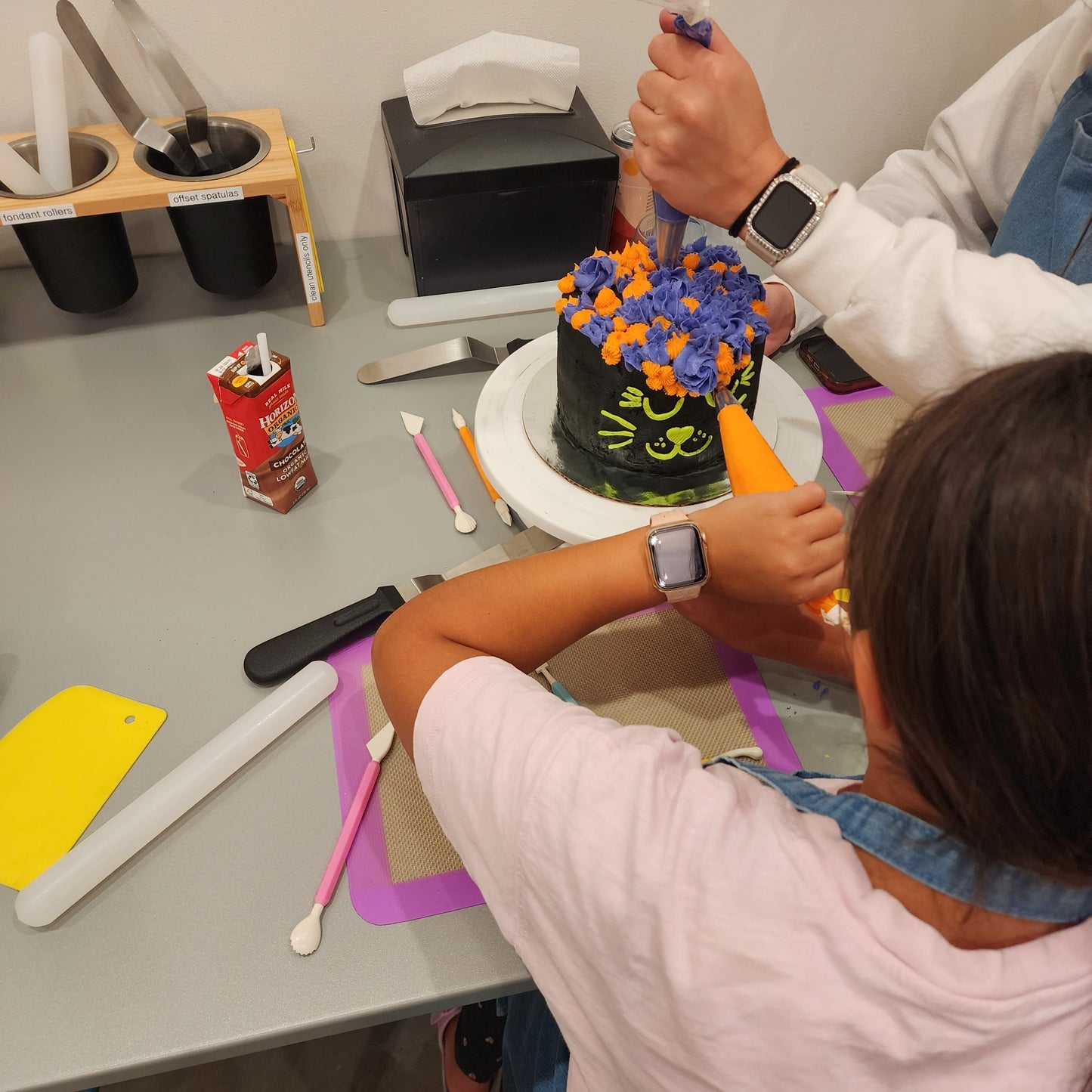 A mom and daughter decorate their Halloween black cat cake at Cake Hoopla in Tigard, near Portland.