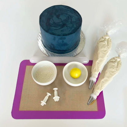 Picture of DIY cake kit To the Moon, including a dark blue cake, yellow fondant, white sprinkles, and white frosting, available for decorating during open studio time at Cake Hoopla near Portland.