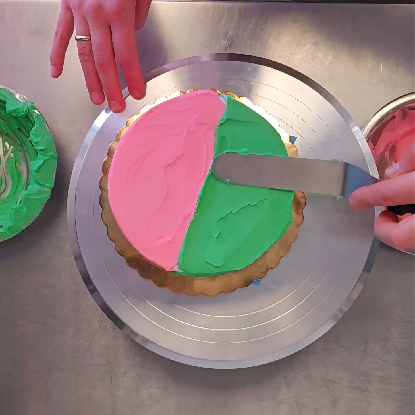 A person decorates at a cake-decorating class at Cake Hoopla in Tigard, near Portland, frosts a cake with pink and green frosting, split down the middle to represent the characters in Wicked.