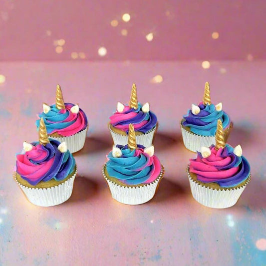 Finished unicorn-themed cupcakes from the Myth Makers cupcake kit. Pink, purple and blue frosting topped with gold-painted unicorn horns, available during open studio time or for pickup at Cake Hoopla in Tigard, near Portland.