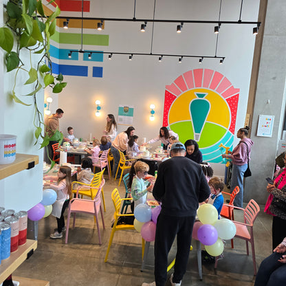 A party with kids and adult decorating cakes at Cake Hoopla during a whole-studio DIY cake-decorating party in Tigard, near Portland.