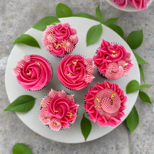 Finished cupcakes from the La Fleur DIY cupcake-decorating frosted with bright pink and light pink rosettes, pointy stars, and little swirls. Small amounts of gold leaf highlight each cupcake. Available as a cake kit during open studio time and to go and as pre-decorated cupcake from Cake Hoopla in Tigard, Oregon near Portland.