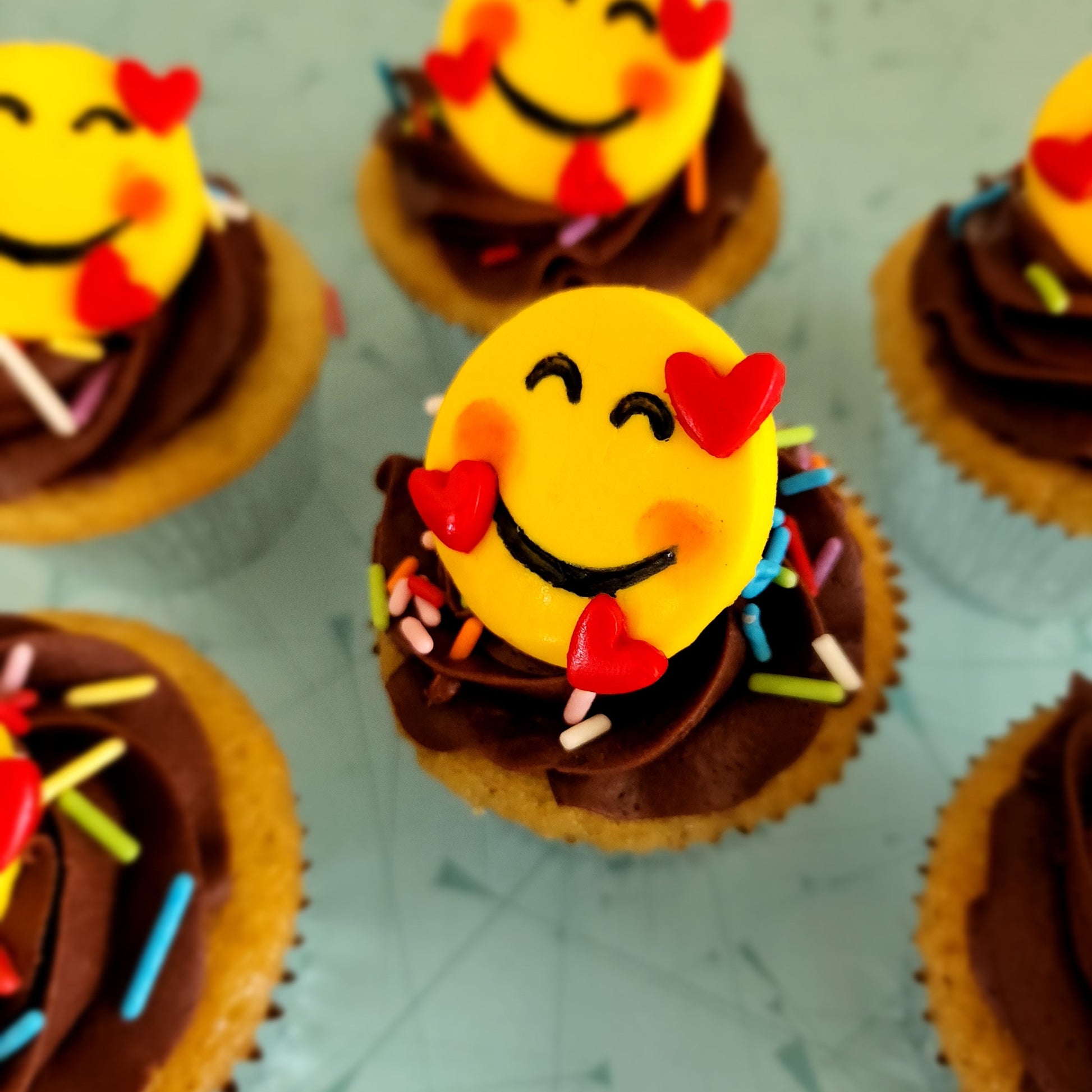 Several emoji DIY cupcakes from decorating kit.  Grateful, thankful, bashful emoji.