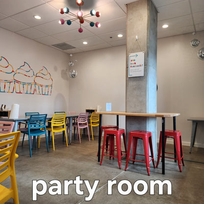 Cake Hoopla's party room, with several tables and bright-colored chairs, chandelier, disco balls and decorations, available to rent for DIY cake/cupcake-decorating parties and events in Tigard, near Portland.