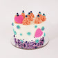 A bright, springtime array of colors on a white frosted cake. Teal frosting stars dot the sides of the cake, mounds of peach-colored frosting circle the top of the cake, and a purple sprinkle mix lines the bottom of the cake. One bright pink fondant heart rests against a frosting mound on top of the cake, and one is pressed into the frosting on the side of the cake. 
