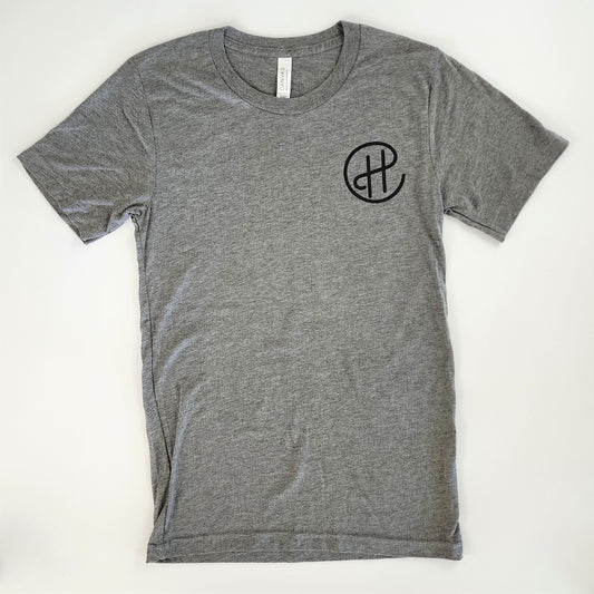 The front of the short-sleeved gray Oregon-wine-country-inspired t-shirt. Over the left breast in black screen printing are the letters "CH" written in a swirly way, where the bar portion of the H extends up to connect with the C, which encircles the H.