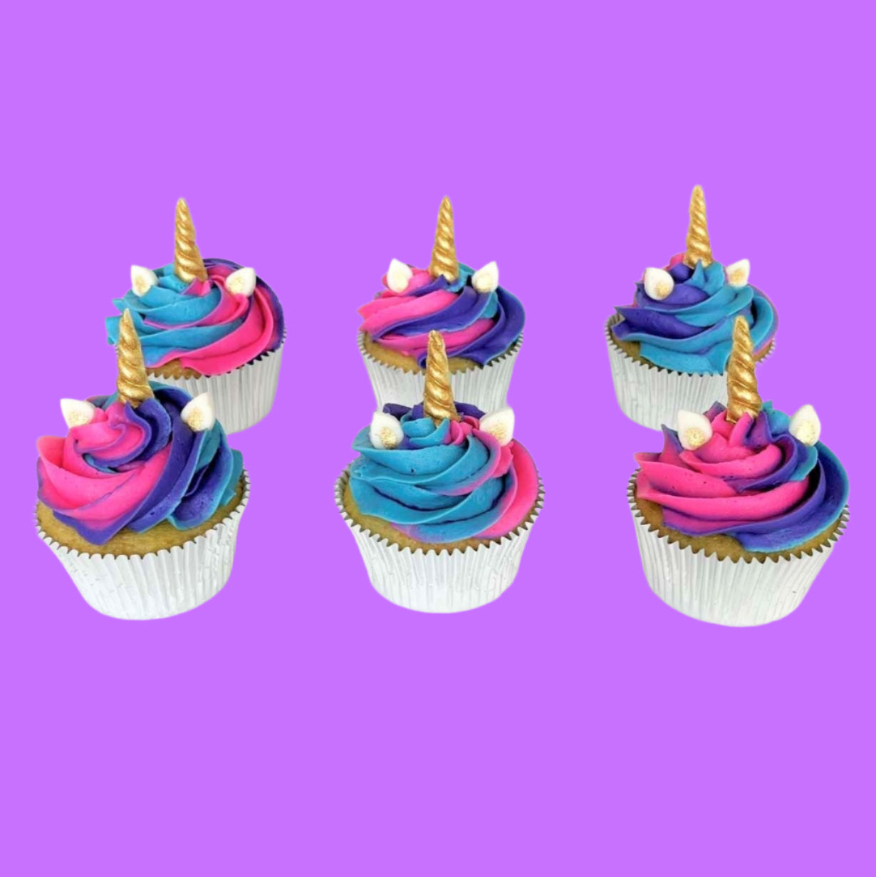 Unicorn-themed cupcakes frosted in blue, purple, and pink swirled frosted, white and gold ears, and gold unicorn horns; a DIY cupcake kit available to decorate during open studio time at Cake Hoopla in Tigard, Oregon, in the Portland area.