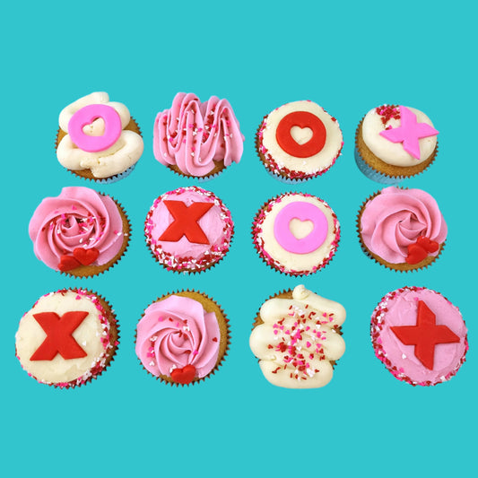 Love-themed XOXO cupcakes frosted pink and white with Xs and Os, hearts, and heart sprinkles; pre-decorated cupcakes shipped to the continental US.