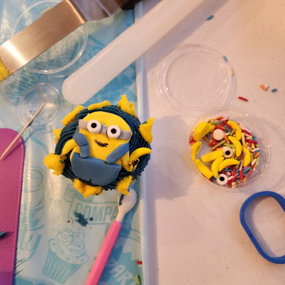 At a DIY cupcake-decorating to-go party, a guest decorated a minion cupcake with yellow fondant, blue overalls, and banana sprinkles.