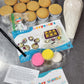 As an example, this shows all the ingredients and materials that go into a cupcake kit. It includes 12 cupcakes, a piping bag with frosting, an edible black marker, pink, yellow, and white fondant, two fondant cutters in a compostable cellophane bag, a colorful instruction card with pictures, a cake care instruction card, and a thank you card. The DIY kits are robust and full of fun components. 