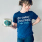 A smiling woman standing 5 feet 9 inches tall and weighing 155 pounds wears the royal blue "go cake yourself” tee. The tee shirt is form fitting, but not too snug, nor too loose. Her upper body is slightly muscular, but the shirt is not too tight against her shoulders or arms. It extends down to the middle of the zipper fly on her jeans, slightly bunching at the hip. 